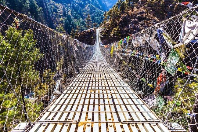 Low angle view of the Dughla Waterfall suspension footbridge with prayer flags located in the Lobuche Valley Nepal