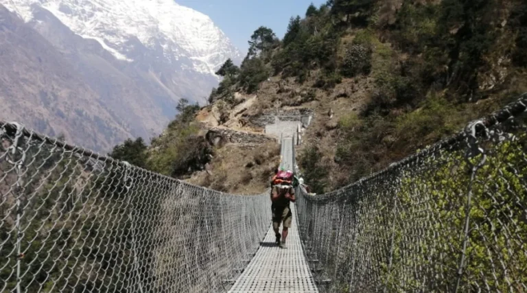 Porter carrying loads at suspension bridge of Manaslu